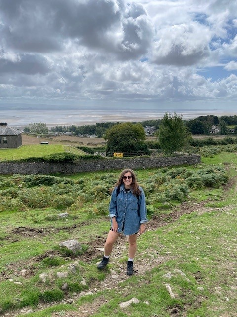 Walker stood on hill in Lake District with views of Morecambe Bay. Route up to Hampsfell Hospice
