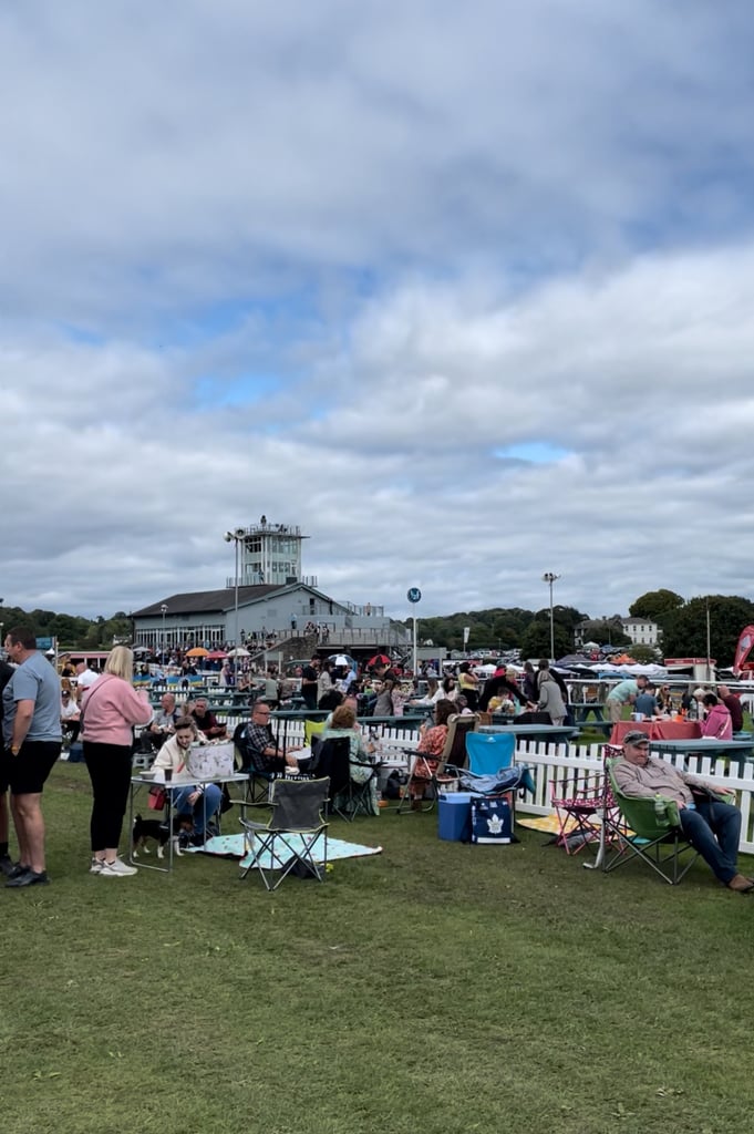 The Grandstand at Cartmel Races and the Cartmel races guide will help where to sit. Race goers sitting in on chairs and picnic blankets next to the course