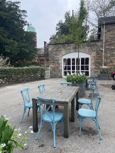 Chairs and tables in the courtyard at the Holker Hall and Gardens cafe. You can see Holker Hall in the background and the traditional blue colour of Holker Hall.