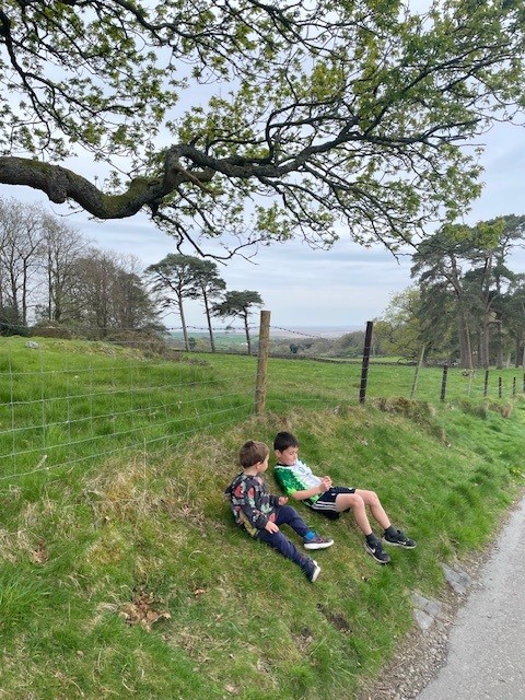 Two young walkers sitting on top of the hill on the way to Holker Hall with views of Morecambe bay.