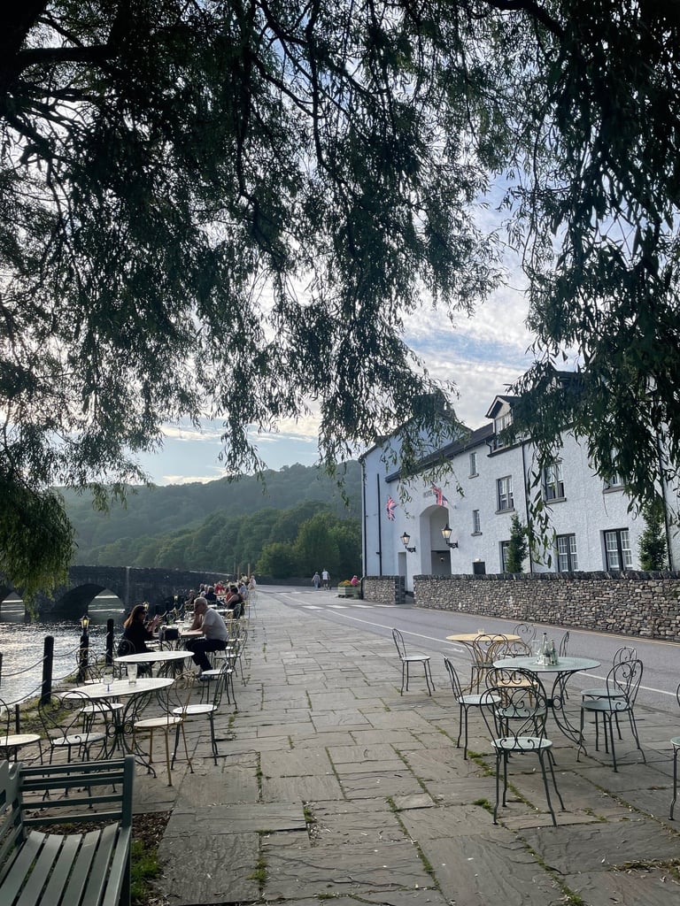 A tree drooping over a seating area at a pub in the Lake District next to the River Leven