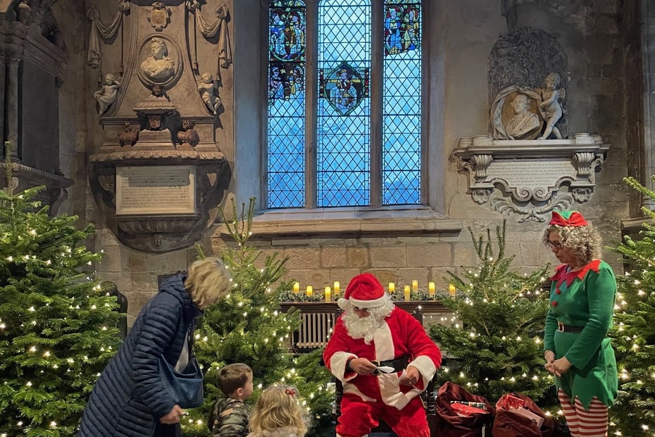Father Christmas giving presents to children in Cartmel Priory the Lake District