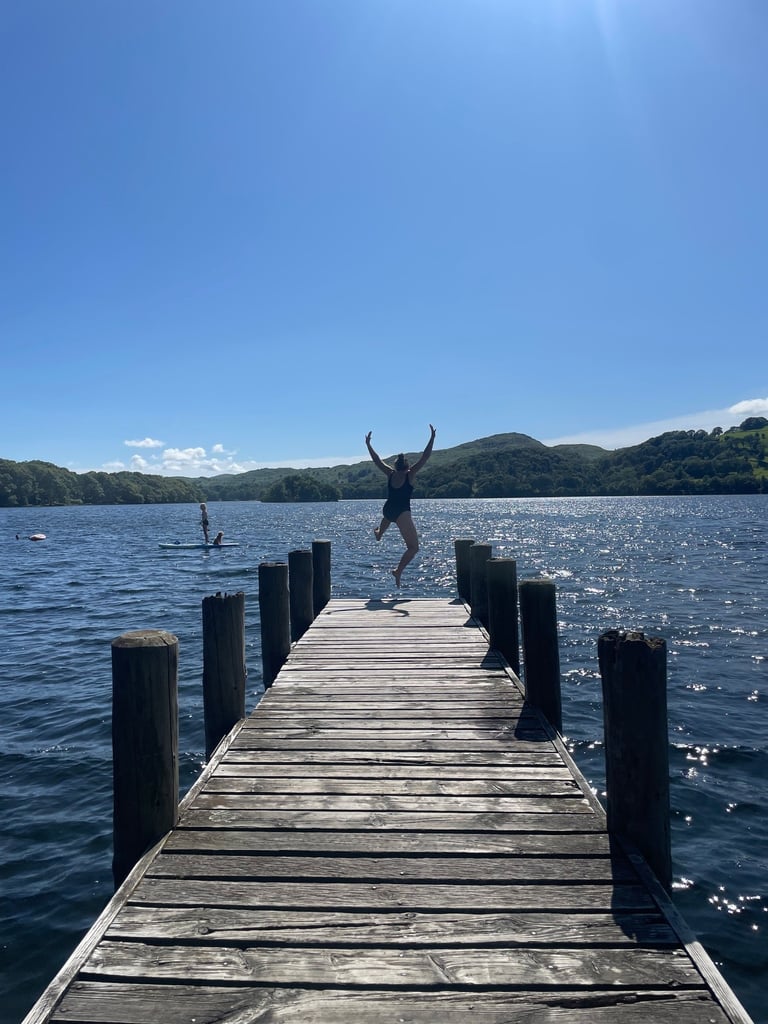Hannah host at the Pheasant Lodge jumping off the end of a Jetty at Coniston Water. A great spot for Lake District wild swimming
