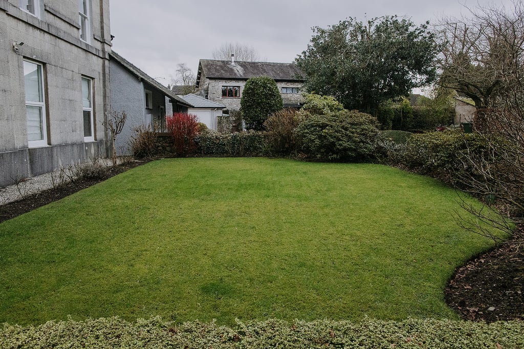 Side garden lawn bordered by shrubs beside The Pheasant Lodge