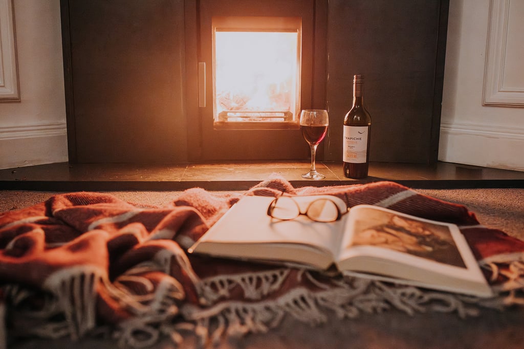 Log burner with book and glass of wine in the Pheasant Lodge lounge