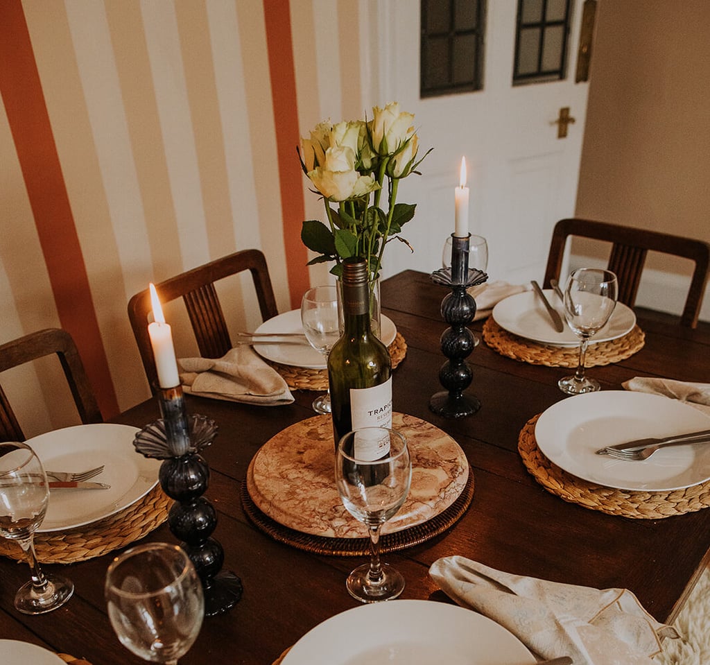 Dining table set for dinner with plates, wine glasses, candles and white roses