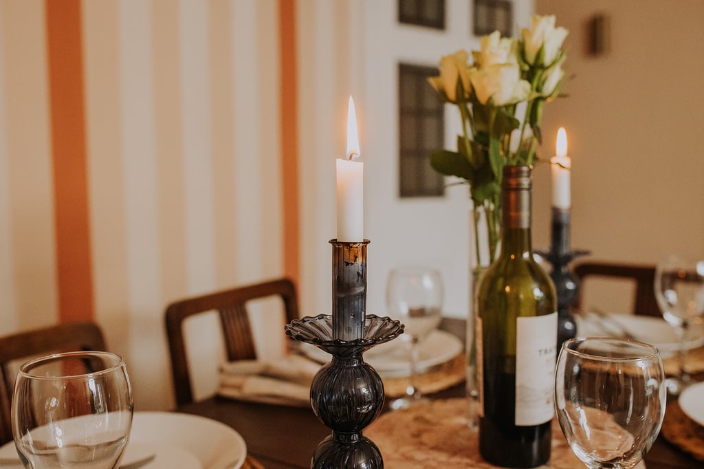 Lit candle, wine glasses and flowers on the dining table