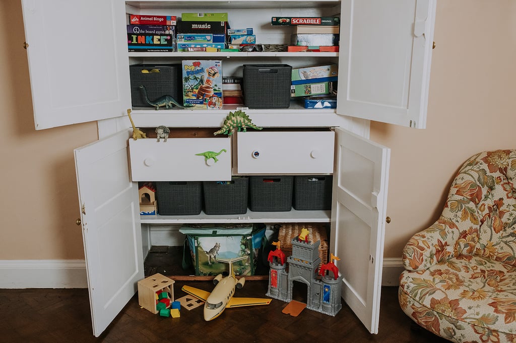 Open games cupboard filled with board games and storage baskets